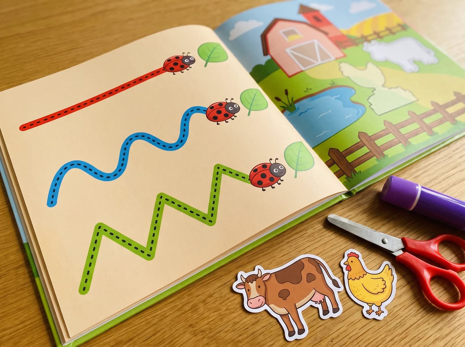 A scissor skills workbook with a page of dotted cutting lines and cut-out animal pieces beside child-safe scissors